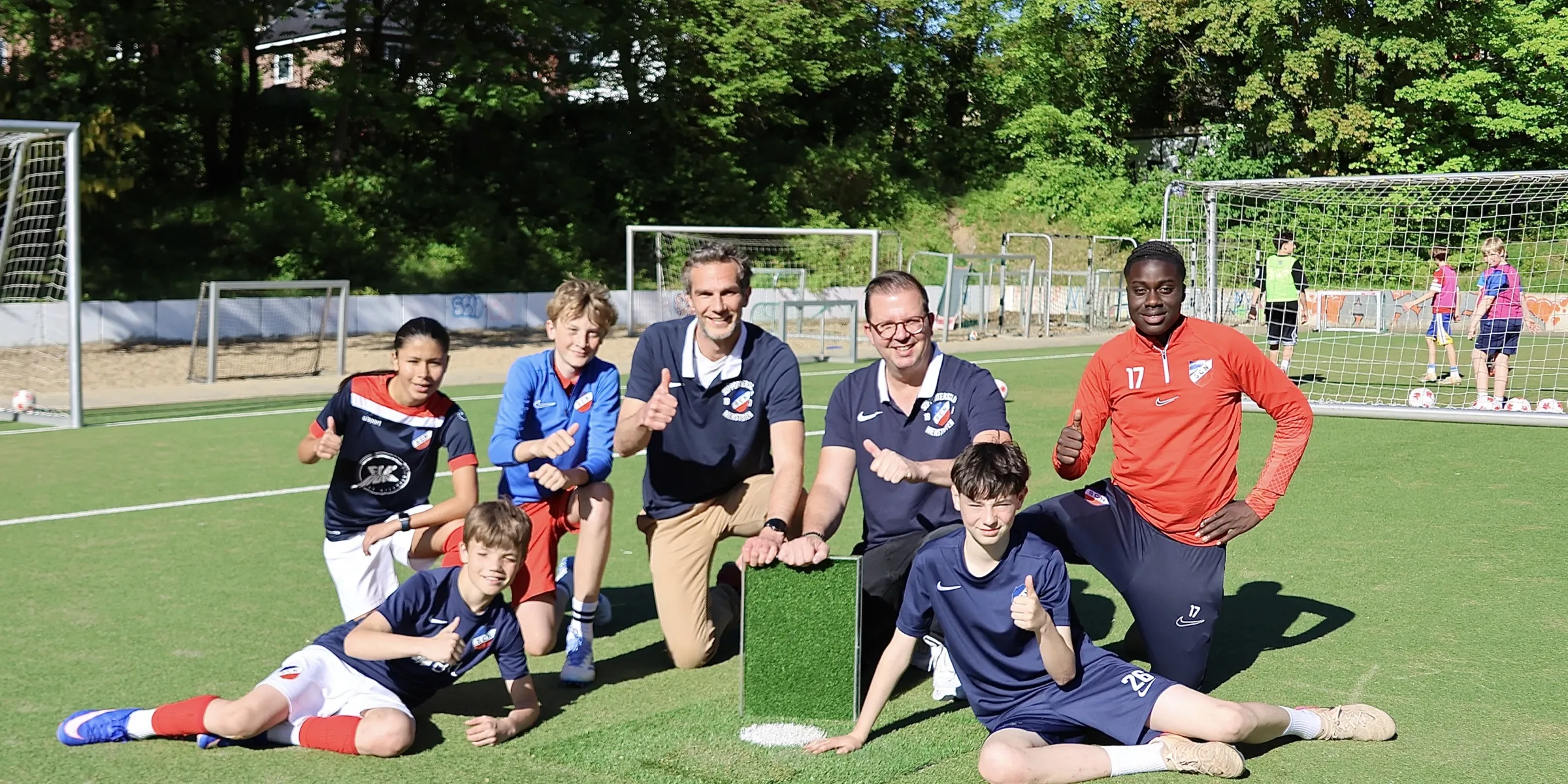 Vorstand und Kinder des SC Nienstedten mit einem Muster des neuen Zukunftsrasens auf dem Platz am Quellental